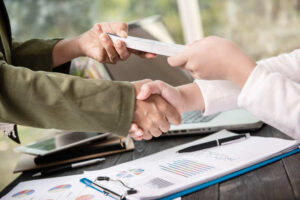 people handshaking and giving cash to another one