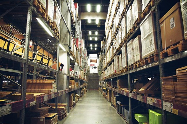 A long warehouse aisle lined with shelves and boxes, illustrating efficient procurement and storage solutions.